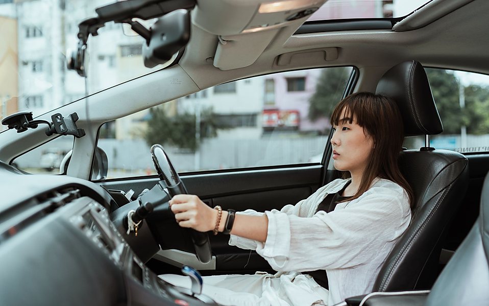 An adult driver at the wheel of a car in traffic